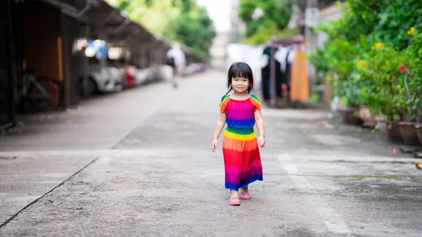 幸せなアジアの子供の女の子が通りを歩いている 子供たちはカラフルな服を着る 子供はにっこり笑った 幼児は3 4歳です 夜のコンセプトの中を歩くと運動 — ストック写真