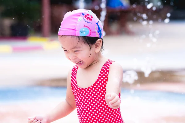 快乐的亚洲小女孩玩水 笑的孩子 孩子们在喷泉里跑来跑去 婴儿戴着粉色的泳帽 穿着带有钻石图案的红色游泳衣 Toddler — 图库照片