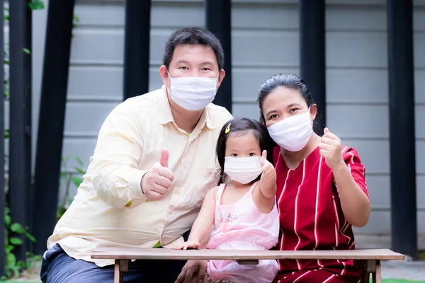 Families wear masks to prevent  spread of coronavirus (COVID-19). Parents and daughters live with new normal idea.  An expression of excellence and success when it comes to wearing mask in normal life.