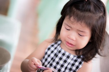 Kız şeker kutusunu açamayınca ağladı. Üzgün çocuk. İstekli çocuklar. Çocuk 3 yaşında ve ekose gömlek giyiyor..