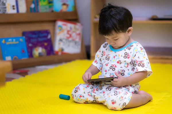 Çocuk oturdu ve sarı kattaki cep telefonuna baktı. Kafanı uzun süre telefonda tutmak, küçük çocuklarda sağlık sorunlarına yol açabilir. Çocuk 2 yaşında..