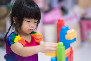 Plastik blok oynayan sevimli küçük kız. Çocuklar plastik bulmaca oynar, hayal gücünü ve el kaslarını güçlendirir. Çocuk 3 yaşında..