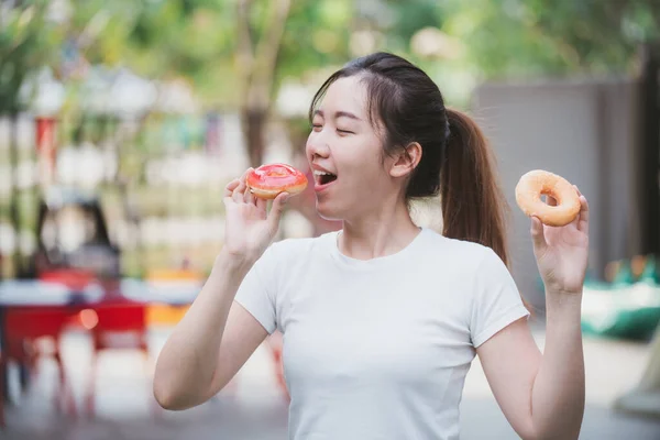 満足したアジアの少女の肖像画のクローズアップは 彼女の家の前でドーナツを食べるのを楽しむ スペースのコピー — ストック写真
