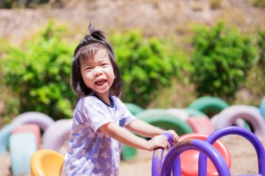 Çocuk eğlence olsun diye atlıkarıncada oynuyor. Küçük kız güldü. Çocuk sıcak güneşin altında oyun bahçesinde oynuyor. Çocuk sağlığı konseptlerine dikkat edin. Bebek 3-4 yaşında..