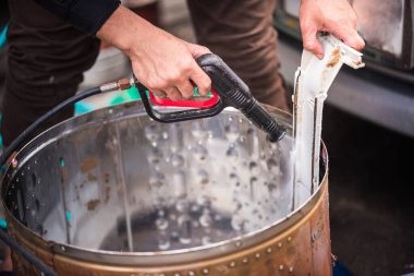 Asyalı adamın elinde yüksek basınçlı bir sprey tabanca vardı. Lekeye su püskürtüyordu. Çamaşır makinesinin varilindeki ekipmanla birlikte..