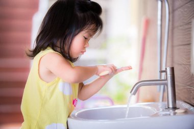 Asyalı küçük bir kız ellerini yıkarken samimiydi. O, sabunu iki eliyle dikkatle ve neşeyle ovuşturdu. Çocuklar sağlığa bayılır. Evde kal. 3-4 yaşlarındaki küçük çocuklar.