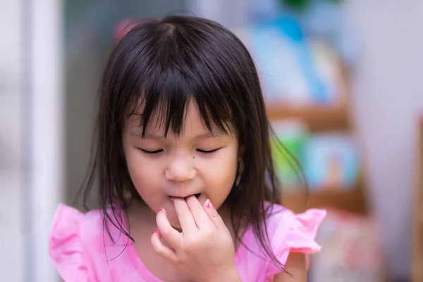 5歳のアジア系の少女が指を口に入れている 食品摂取量における子供の健康と清潔感の概念 夏や春の家で — ストック写真