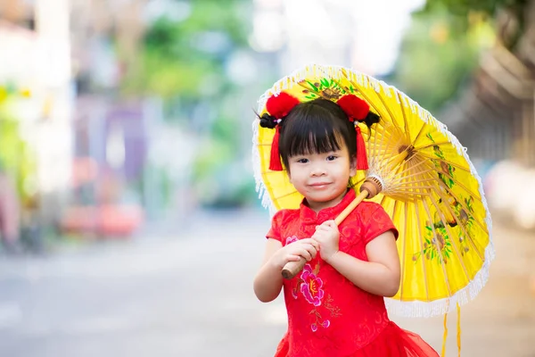 中国の旧正月のコンセプト 可愛いアジア系の女の子は チョンサムやチパオの赤いドレスを着て 毛皮のような赤いクリップで彼女の髪を飾ります 幸せな子供甘い笑顔 黄色の傘のヴィンテージスタイルを保持子供 — ストック写真