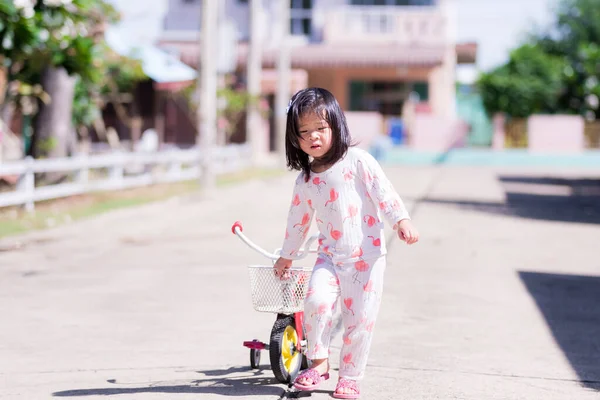 子供は村の道路を自転車で歩く 夏の朝や春 子供たちは暑い中を歩く 暑い天気と朝の物理的な活動の後で子供の顔に汗をかきます 可愛いです女の子3 — ストック写真