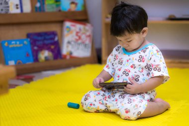 Kafası aşağıda oturan ve animasyonu küçük bir akıllı telefondan izleyen küçük bir çocuğun fiziksel sağlık ve gelişim üzerinde olumsuz etkileri olabilir. Çocuk 1-2 yaşlarındaydı. Bulutlu bir günde