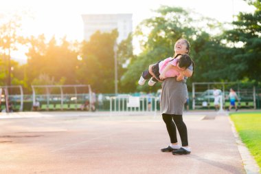 Konsept içinde zaman geçirmekten mutlu aile. Annem kızıyla mutlu bir şekilde oynadı. Annem kızı kucağına aldı ve etrafta uçak gibi süzüldü. Aile mutluluğu, birlikte güldük. Sıcak bir yaz günü halka açık spor salonunda..