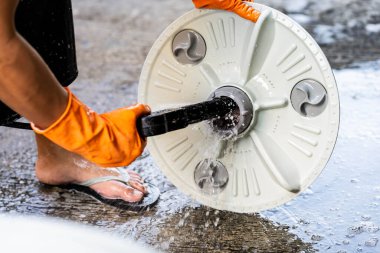 Çamaşır makinesi, çamaşır makinesinin tabanındaki inatçı kiri temizlemek için yüksek basınçlı hortum kullanır. Beton bir yolda.