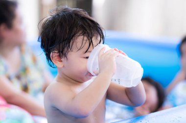 Tatlı çocuk plastik bardaktan su içmiş. Çocuklar yorgun düşene kadar suda oynadıktan sonra susarlar. Oğlu 1-2 yaşlarında..