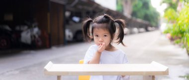 Kız yedikten sonra meyve tohumunu tükürdü. Çocuklar portakal yemeyi öğrenirler. Evin önündeki piknik alanında. Boş ahşap masa küçük çocuğun önüne kurulur. Beyaz elbiseli çocuklar 3-4 yaşındalar.