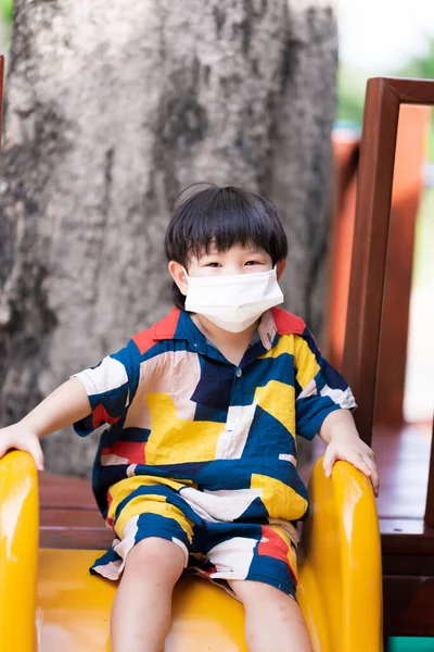 Αξιολάτρευτο Αγόρι Ιατρική Μάσκα Προσώπου Όμορφο Μωρό Παίζει Κίτρινο Σλάιντ — Φωτογραφία Αρχείου