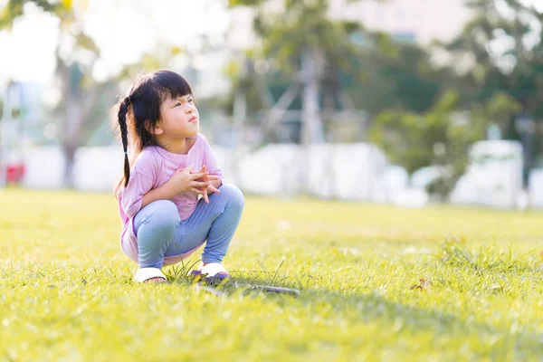 夏天或春天的时候 快乐的亚洲小孩蹲在绿色的草坪上 孩子们做可爱的脸 看着上面 可爱的女孩 有放松的时间 复制空间 — 图库照片