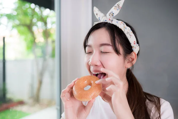 幸せなアジアの若い女性はおいしく甘いドーナツでかむ — ストック写真