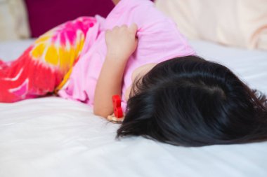 Asyalı kız çocuğu tahta oyuncağıyla yatakta uyuyor. Yatağında uyuyan sevimli çocuk oyuncağı. Çok tatlı uykucu bir kızım var. 4-5 yaşlarında bir bebek..