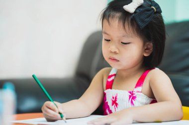 Close-up image cute girl pupil coloring on a homework during an on hands lesson. Online education concept. Kindergarten aged 4-5 years old.