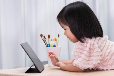 Şirin Asyalı kız derse başlamadan önce öğretmeniyle internette görüntülü konuşma yaparken eğleniyor. Öğrenci çocuk sıkılmasın diye derse sokuyorum. 4-5 yaşlarında bir çocuk..