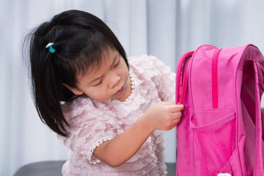 Okul konseptine geri dönelim. Öğrenci çocuk okula başlamadan önce eşyalarını hazırlamak için çantalarının fermuarını çekiyor. Çocuklar okula gitmek için sabırsızlanıyorlar..