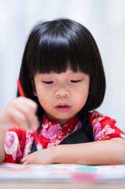 Dikey görüntü. Boyalı fırça kullanan küçük sanatçı kız suluboya karikatür çiziyor. Mutlu çocuk dersini sınıfta öğreniyor..