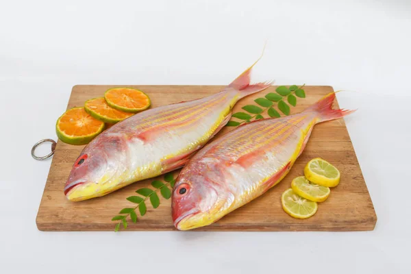Limon dilimi, portakal dilimi ve ahşap bir defter üzerinde köri yapraklarıyla süslenmiş taze Pembe Perch 'in (iplikçik şeklinde) yakın görüntüsü, Beyaz Arkaplan, Seçici odak.