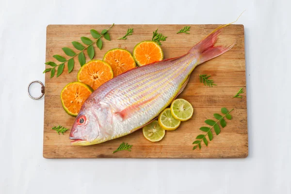 Limon dilimi, portakal dilimi ve ahşap bir defter üzerinde köri yapraklarıyla süslenmiş taze Pembe Perch 'in (iplikçik şeklinde) yakın görüntüsü, Beyaz Arkaplan, Seçici odak.