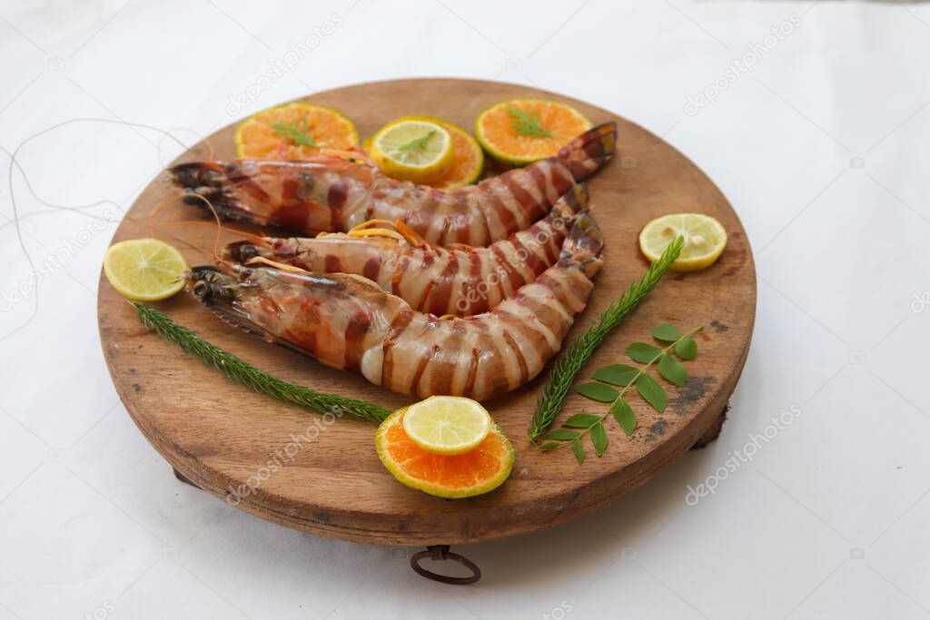 Fresh Giant Tiger Shrimp decorated with spices and herbs on a wooden pad.Isolated on white background.