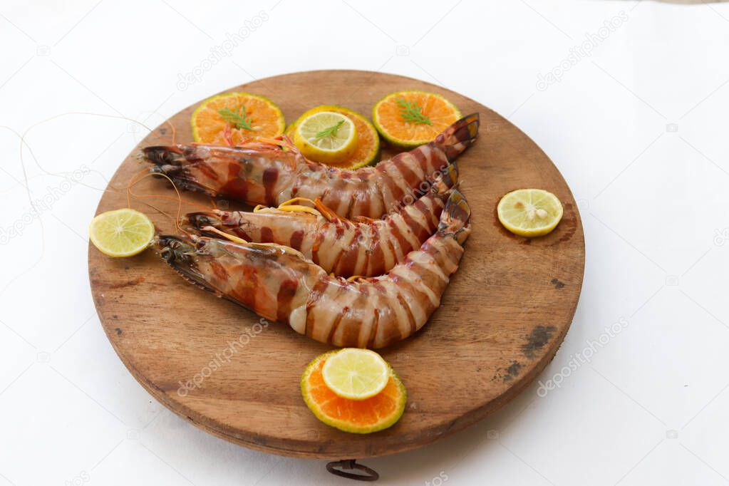 Fresh Giant Tiger Shrimp decorated with spices and herbs on a wooden pad.Isolated on white background.