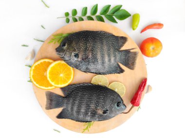 İnci benekli balık / Karimeen otlar ve meyvelerle süslenmiş. Beyaz arkaplanda izole edilmiş. Seçmeli odak.