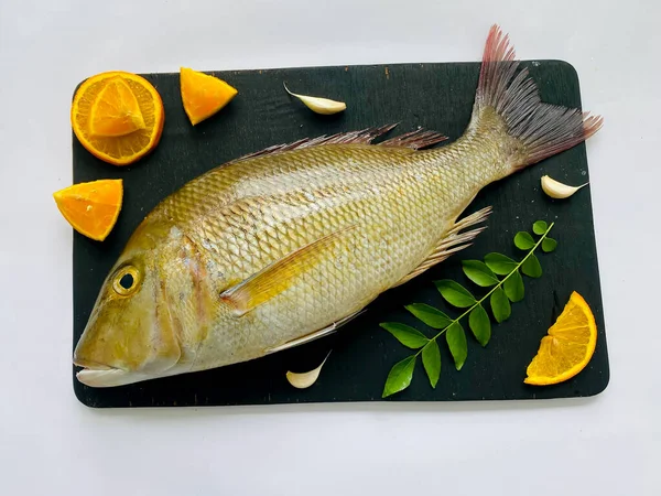 新鲜的帝王鱼 用香草和蔬菜装饰在黑色的挂毯上 — 图库照片