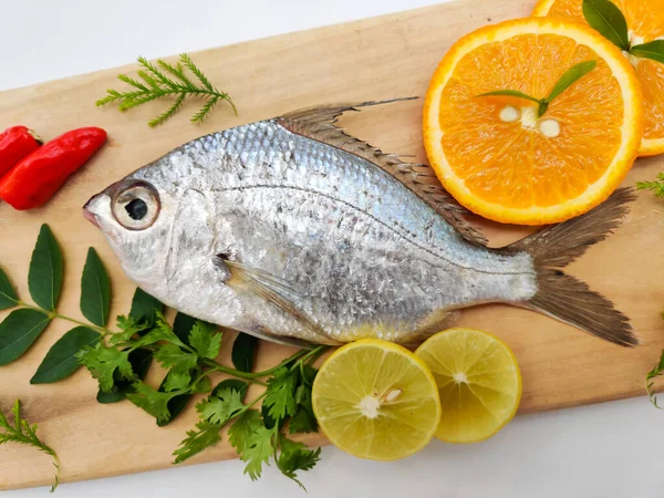Gerres Fish (Gerres Filamentosus), Whipfin gümüşi kocakarı balığı, ahşap yastıktaki köri yaprakları ve domates ile süslenmiştir..
