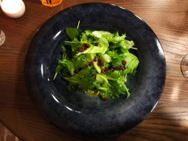Güzel siyah tabakta marullu yeşil salata. Tahta masada nefis sıcak sığır eti salatası. Restoran yemeği.