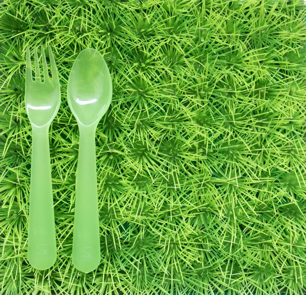 Grön bakgrund för en picknick med gräs och en gaffel och sked — Stockfoto