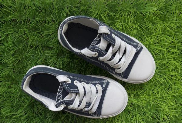 Yeşil çimenlerin üzerinde bebek spor ayakkabı. Üstten Görünüm