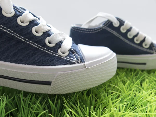 Klasyczne buty do biegania, dzieci na zielonej trawie i biały backgro — Zdjęcie stockowe