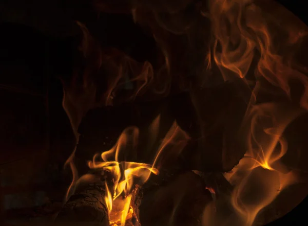 Siyah bir zemin üzerine şöminede yanan odun
