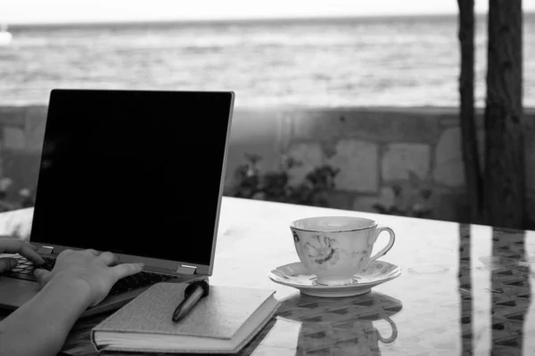 Woman working seaside on laptop and drink coffee, remote professional work life in holiday, home office