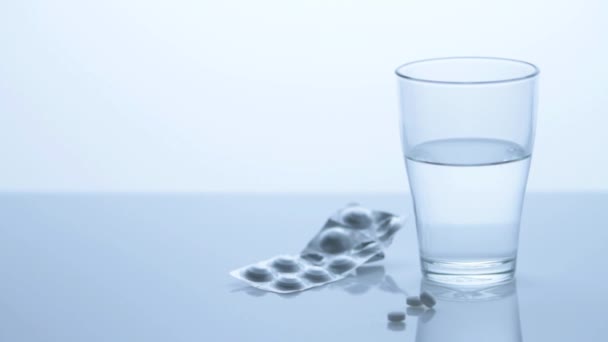 Un vaso de agua con una tira de blister farmacéutico — Vídeos de Stock