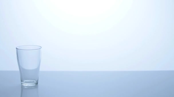 Vaso de agua sobre fondo azul — Vídeos de Stock