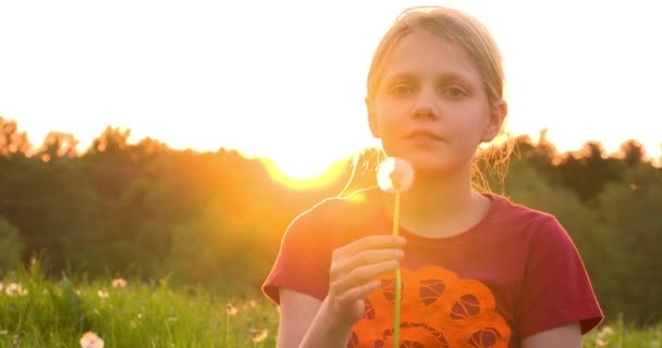 Девушка, дующая на цветок одуванчика — стоковое видео