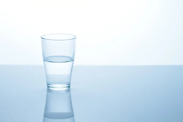Glas met water op tafel Stockfoto