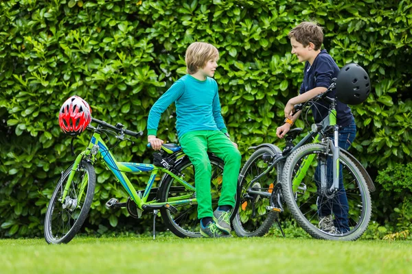 Два мальчика в саду с велосипедами — стоковое фото
