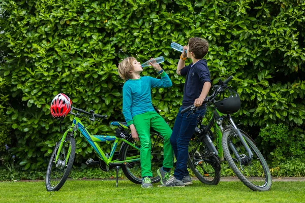 Two boys in a garden with bikes — Stock Photo, Image