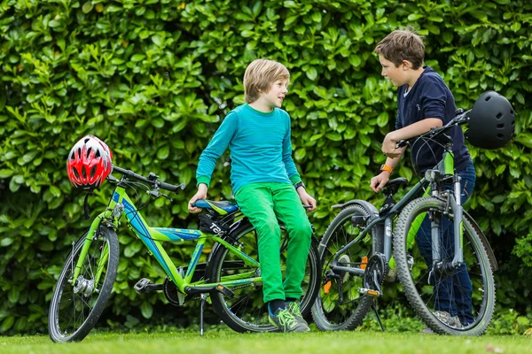 Twee jongens in een tuin met fietsen Rechtenvrije Stockfoto's