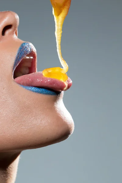 Woman dripping honey on her tongue Stock Photo