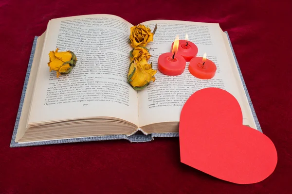 Drie rode kaarsen liggend op het boek met rood hart 2 — Stockfoto