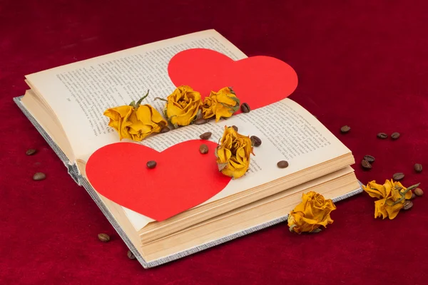 Four roses and two hearts lying on the book with coffee beans — Stock Photo, Image