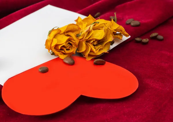 Corazón rojo acostado en un sobre con rosas secas y granos de café —  Fotos de Stock